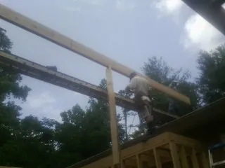Carpenter setting a ridge beam over a new addition frame — Ice Dam Removal by Roofing Brothers in East Killingly