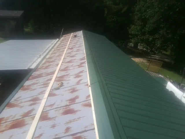 Old rusted panels beside newly installed green metal roofing — Wind Damage Roof Repair by Roofing Brothers in East Killingly