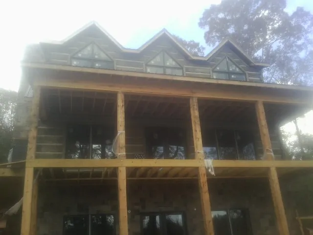 Dormers and porch framing on a large log home under construction — Roof Coating work by our crew in East Killingly