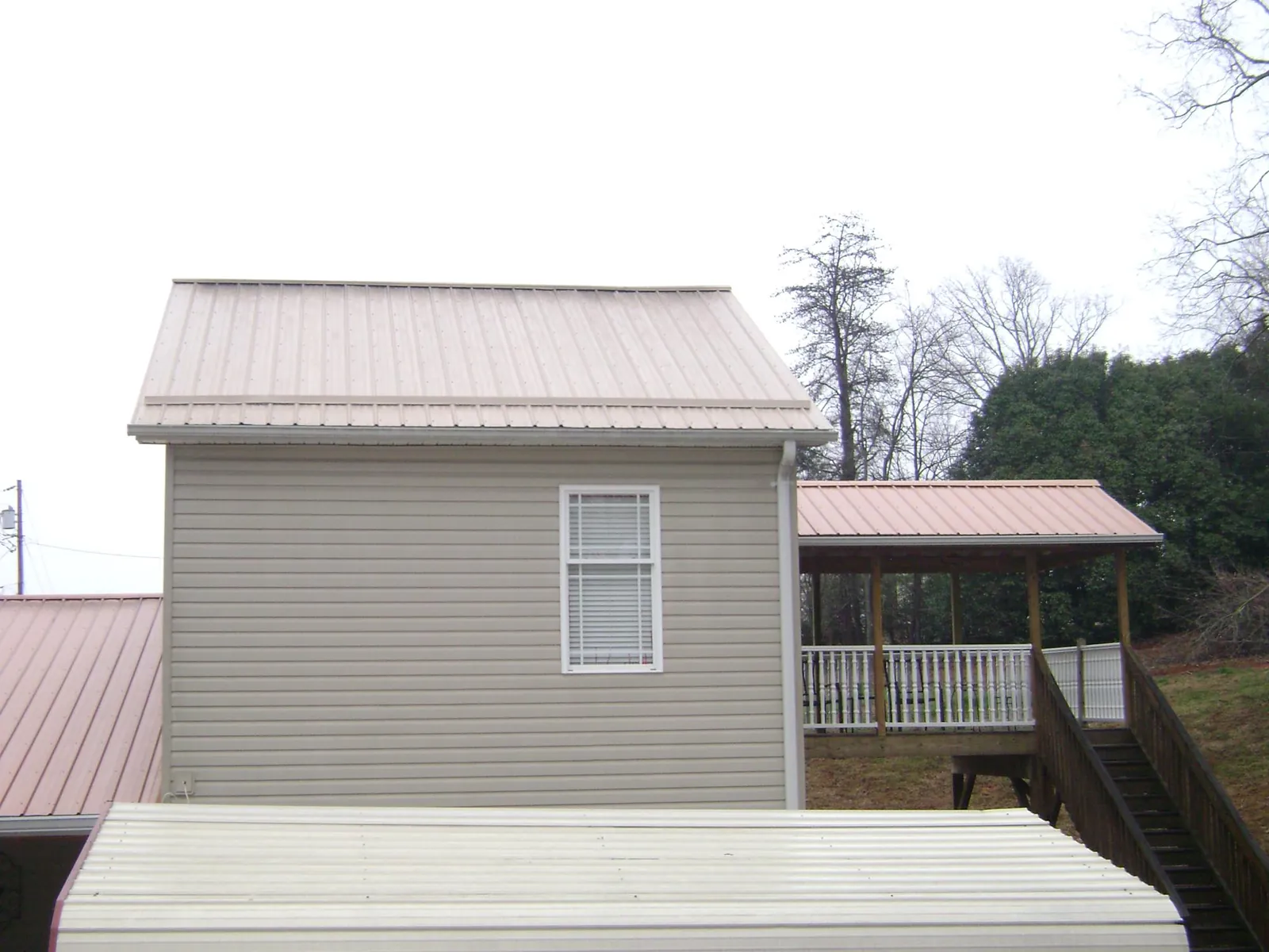 Tan metal roofs on a two story addition and attached porch, from a Roof Replacement job in East Killingly