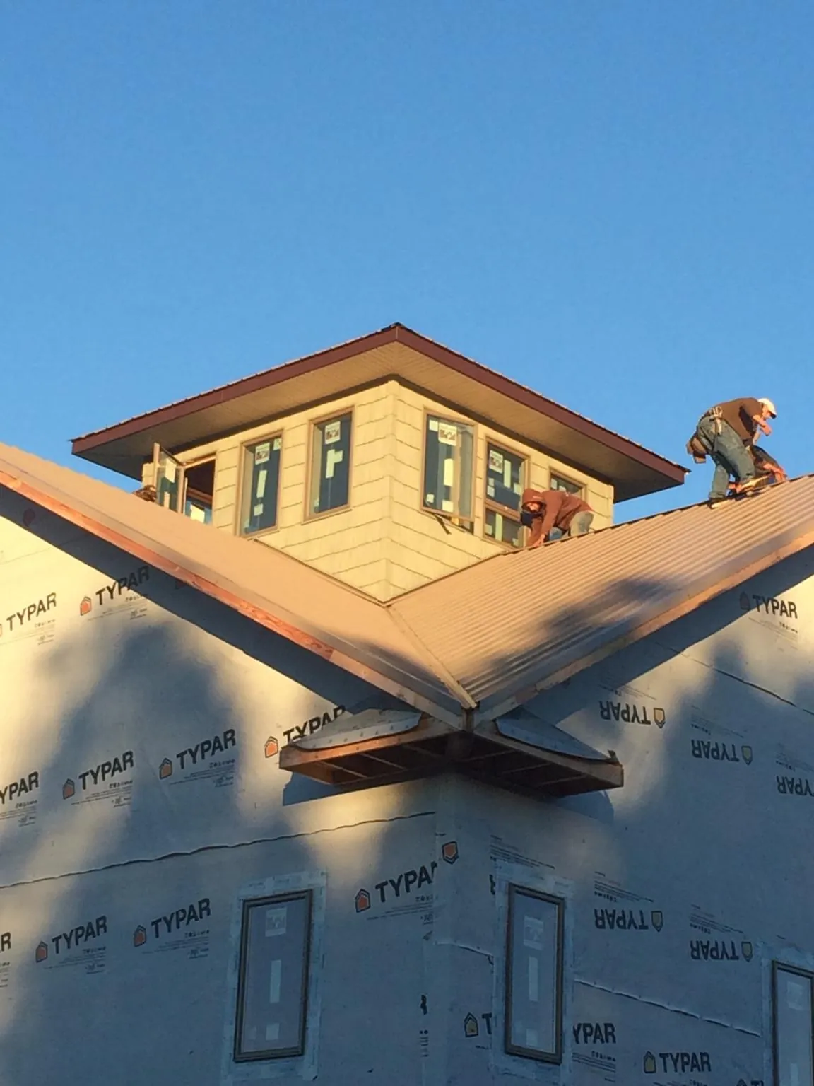 Roofers working around a rooftop cupola on a new metal roof at sunset — Roof Waterproofing in East Killingly by Roofing Brothers